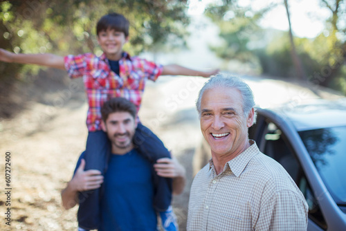 Portrait of happy multi-generation men outside car