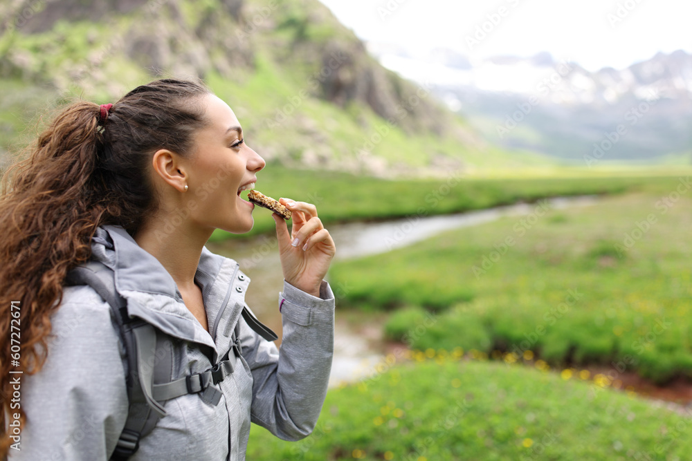 Fototapeta premium Hiker eating cereal bar in a valley