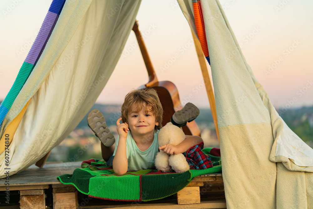 Child sitting in tent at summer camp. Camp dream. Kid dreams in tent outdoor. Childhood dream. Daydreamer child. Dreams and imagination. Dreamy kids. Cute kid spend summer holidays. Child sitting in tent at summer camp. Camp dream. Kid dreams in tent outdoor. Childhood dream. Daydreamer child. Dreams and imagination. Dreamy kids. Cute kid spend summer holidays.