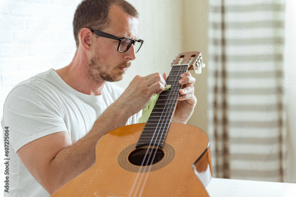 Maintenance of musical instruments. Guitar master polishing fretboard