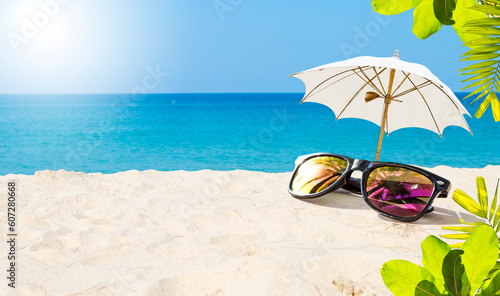 Tropical summer background, sunglasses with umbrella on sandy beach, summer outdoor day light