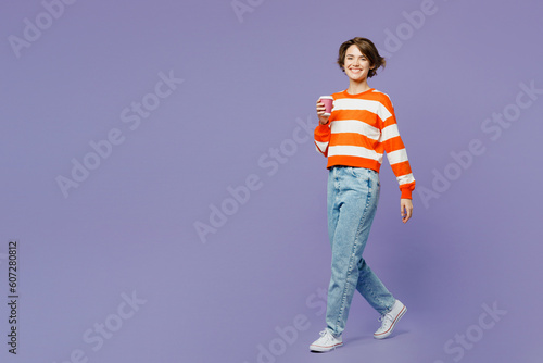 Full body young woman she wear casual clothes sweatshirt hold takeaway delivery craft paper brown cup coffee to go isolated on plain pastel light purple background studio portrait. Lifestyle concept.
