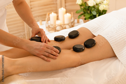 Woman getting a hot stone  massage therapy in spa salon 	