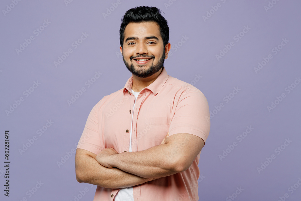 Young happy fun cool Indian man wearing pink shirt white t-shirt casual clothes holding hands crossed folded isolated on plain pastel light purple color background studio portrait. Lifestyle concept. Young happy fun cool Indian man wearing pink shirt white t-shirt casual clothes holding hands crossed folded isolated on plain pastel light purple color background studio portrait. Lifestyle concept.