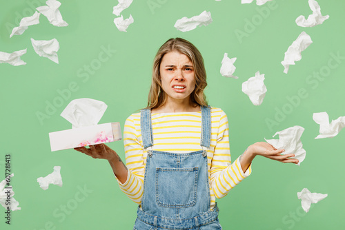 Murais de parede Sick unhealthy ill allergic woman has red watery eyes, runny stuffy sore nose suffering from allergy trigger symptom hay fever hold paper napkin sit at table isolated on plain green background studio