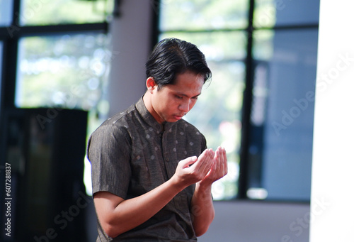 an asian muslim man is praying raising his hands © Naufal