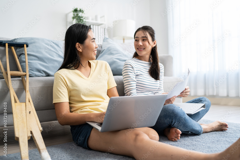 Asian woman amputee using laptop computer with friend in living room. Asian woman amputee using laptop computer with friend in living room.