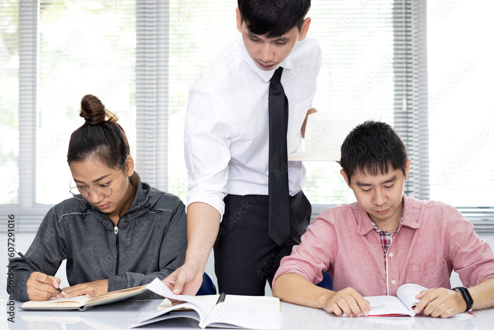Asian male teacher is standing and teaching to students in the classroom. Asian male teacher is standing and teaching to students in the classroom.