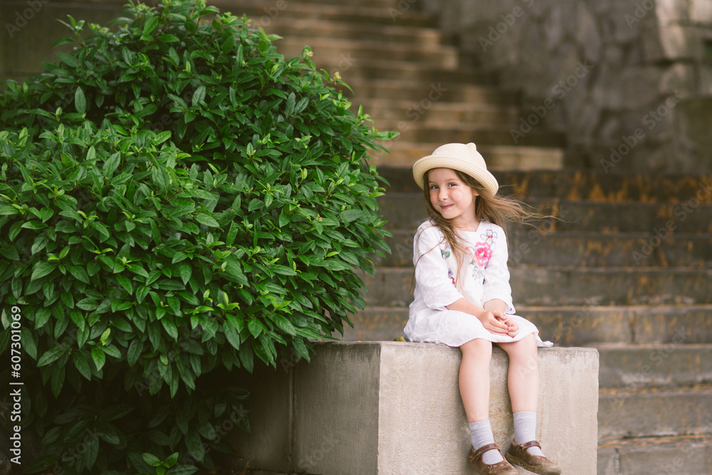 Obraz premium happy cute baby child girl sitting in city on street outdoor in summer