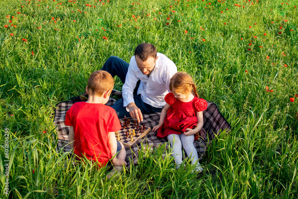 Fototapeta premium father and children. dad and son play chess on a picnic