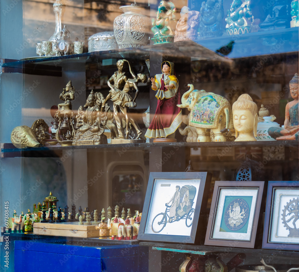 Human figures, toys, photo-frames and Hindu God idols on display with glass pane and a pigeon bird's reflection on it. Human figures, toys, photo-frames and Hindu God idols on display with glass pane and a pigeon bird's reflection on it.