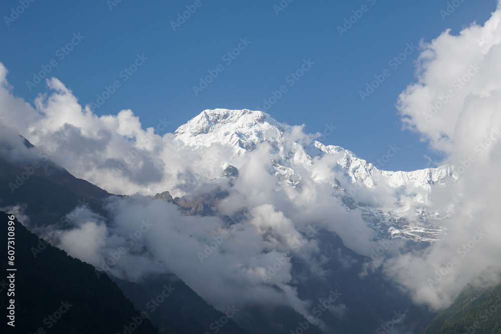 Selective focus Annapurna South peak with white snow and fog with noise and grain in bright sunlight