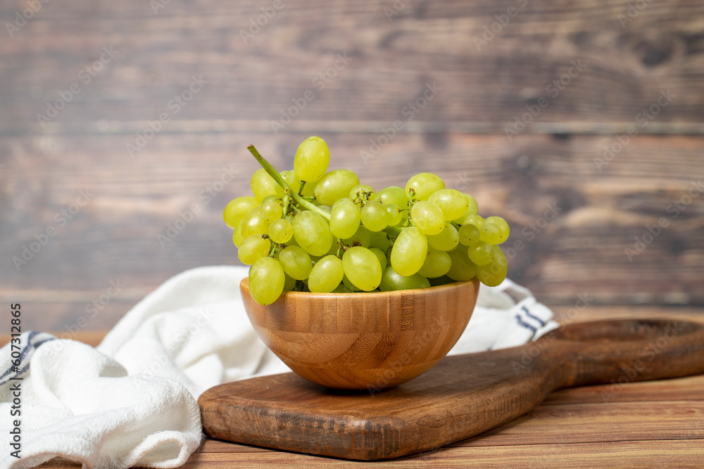 Green grapes in bowl. Organic farm products. Fresh bunch of grapes on wooden background Green grapes in bowl. Organic farm products. Fresh bunch of grapes on wooden background