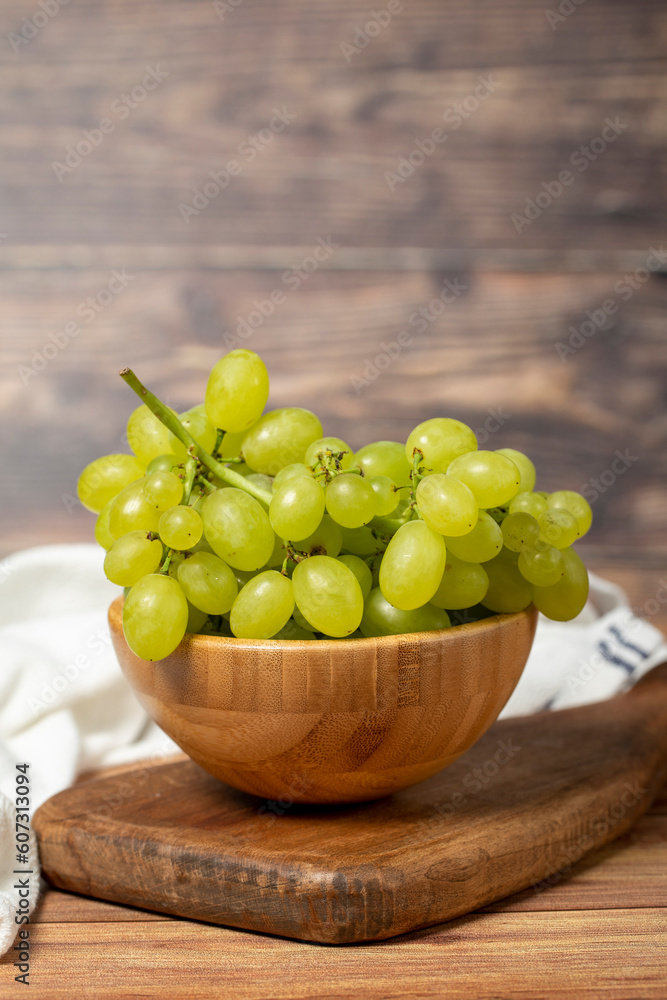 Green grapes in bowl. Organic farm products. Fresh bunch of grapes on wooden background Green grapes in bowl. Organic farm products. Fresh bunch of grapes on wooden background