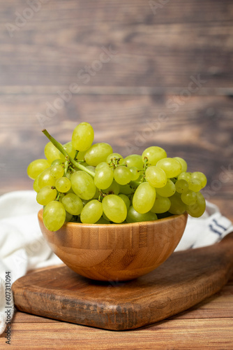 Green grapes in bowl. Organic farm products. Fresh bunch of grapes on wooden background