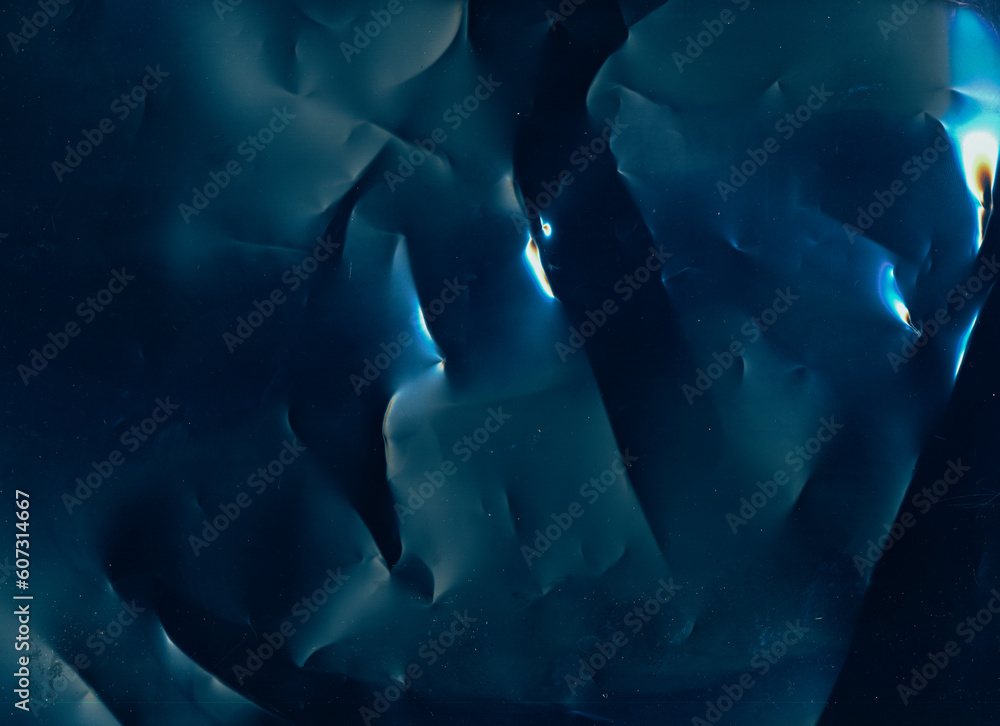Obraz premium Weathered film. Dust scratches texture. Crumpled noise overlay. Blue orange white color light flare on dark rough creased foil surface illustration abstract background.