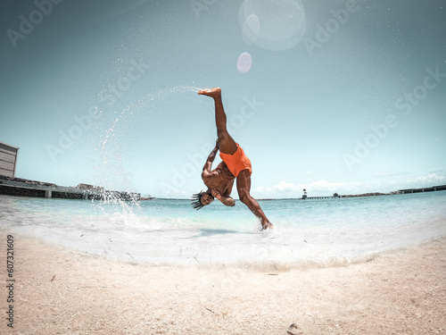 Fit man performs flips at the beach