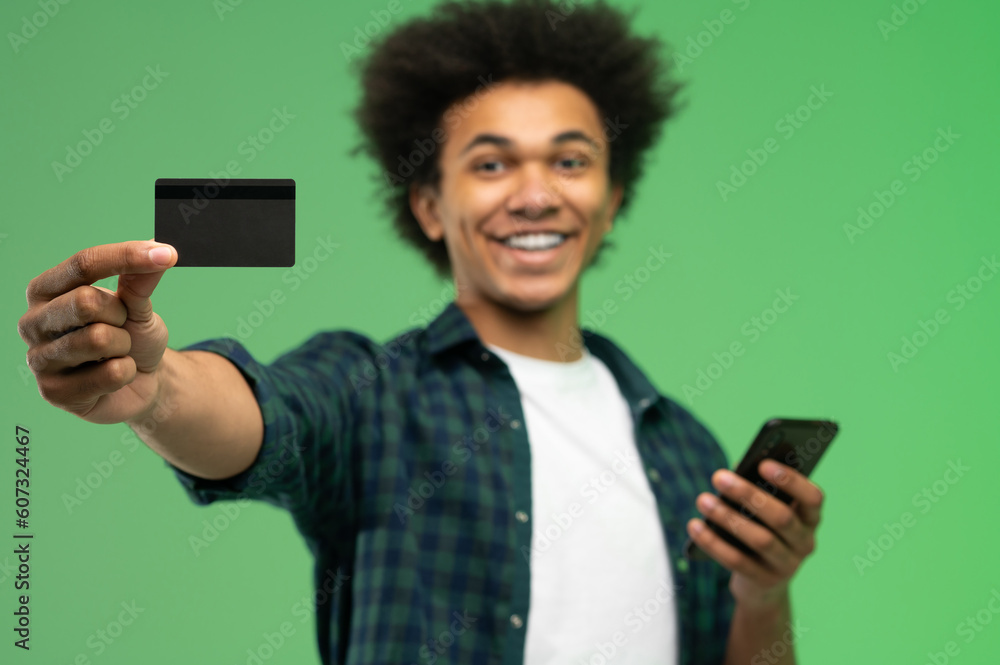 African american young guy with smartphone and credit card in hands African american young guy with smartphone and credit card in hands