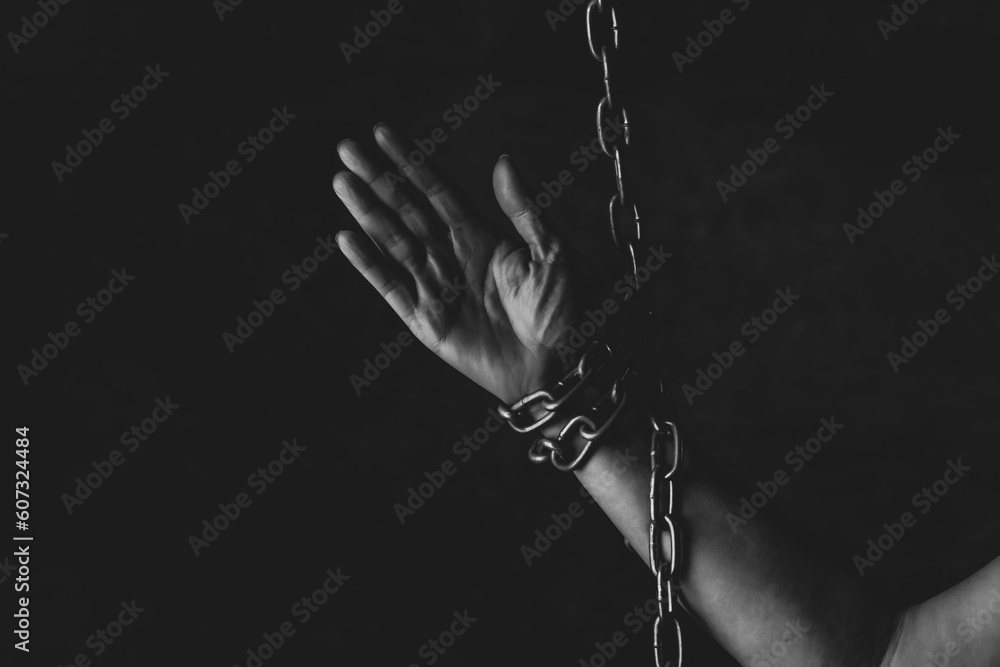 Mano de persona encadenada sobre fondo negro en estudio, sensacion ...