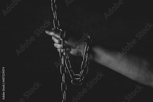 Mano de persona encadenada sobre fondo negro en estudio, sensacion falta de libertad, prision 