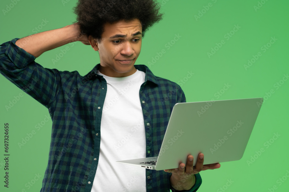 Young african american guy in checkered shirt with a laptop Young african american guy in checkered shirt with a laptop