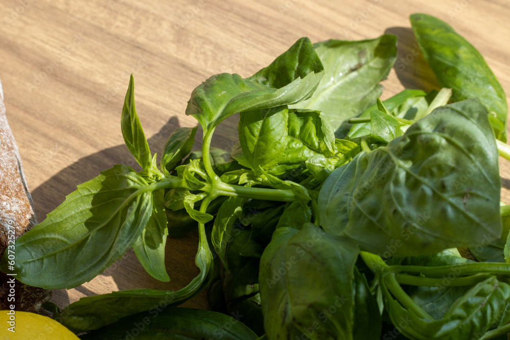 a bunch of basil leaves left on wooden table in sunlight a bunch of basil leaves left on wooden table in sunlight
