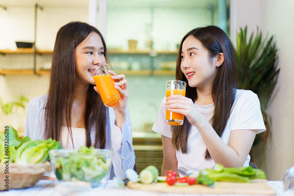 Asian women enjoying eating a breakfast and drinking organic orange juice together in the dining room. Asian women enjoying eating a breakfast and drinking organic orange juice together in the dining room.