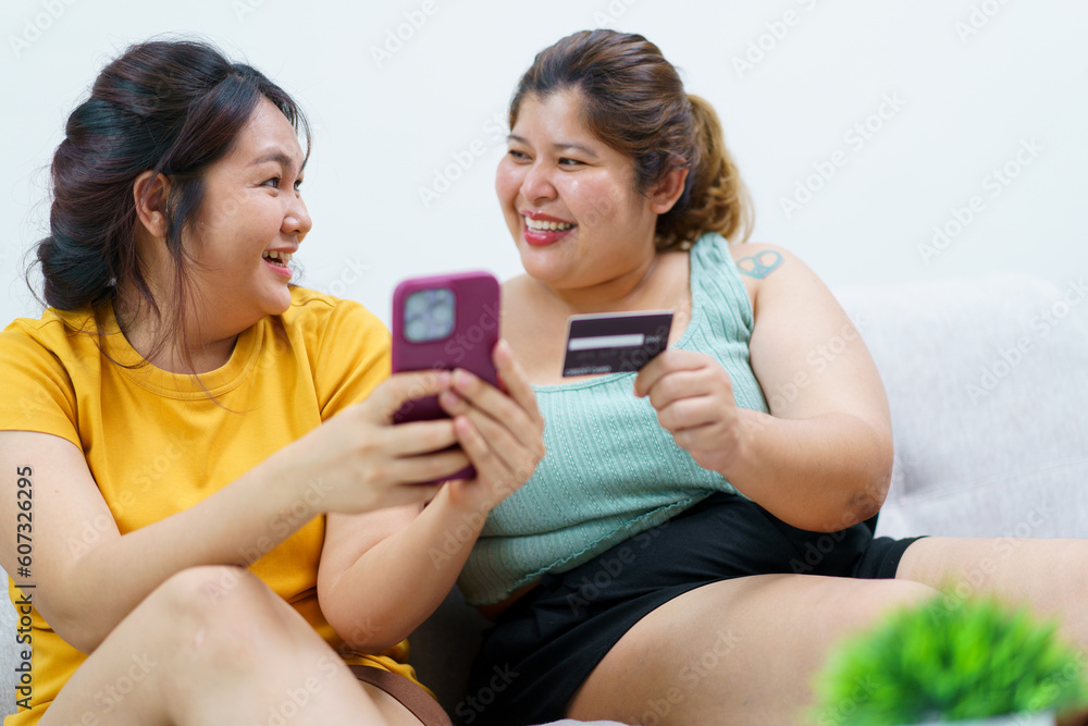 Two Asian fat women staying together and buying goods in e-commerce website. Two Asian fat women staying together and buying goods in e-commerce website.
