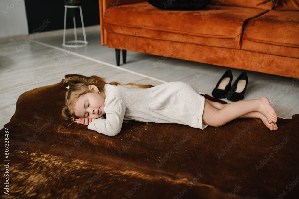 Baby sleeping in living room. Little girl is lying down on a carpet on