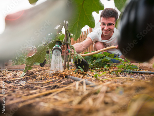 Joven horticultor regando el huerto de su nuevo estilo de vida. Vida sostenible / Young horticulturist watering the garden of his new lifestyle. Sustainable living.