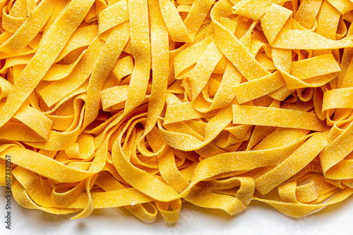 Obraz na plátně Homemade fresh, uncooked tagliatelle or fettuccine background,  is a traditional type of italian pasta