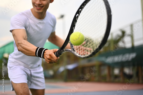 Shot of male athlete hitting ball with racket on outdoor court. Fitness, sport, exercise concept © Prathankarnpap