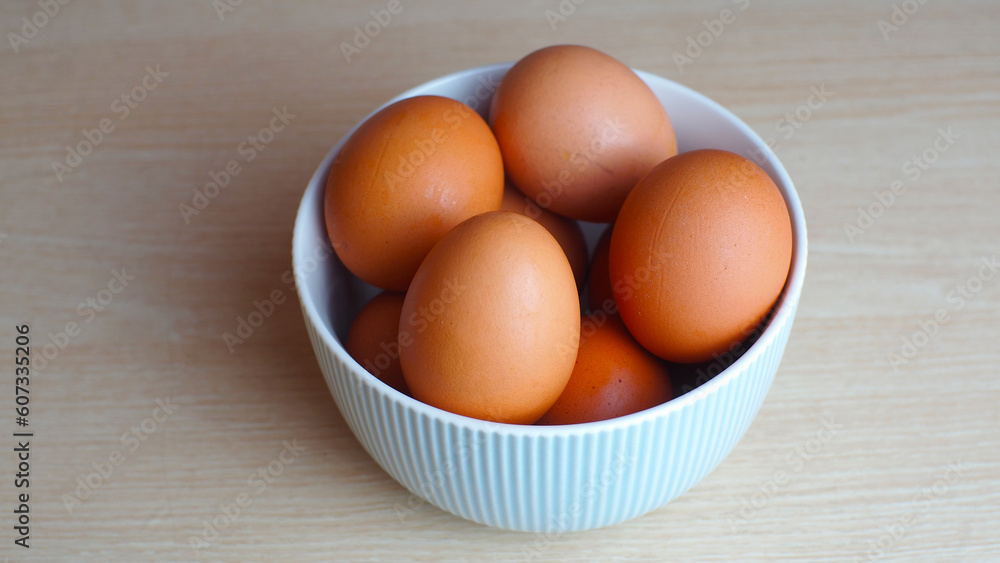 Fresh eggs in ceramic bowl on wooden table as a background with copy space Fresh eggs in ceramic bowl on wooden table as a background with copy space