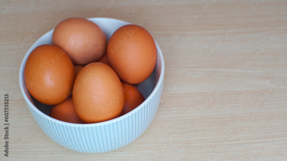 Fresh eggs in ceramic bowl on wooden table as a background with copy space Fresh eggs in ceramic bowl on wooden table as a background with copy space