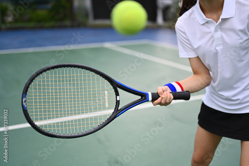 Sportive young woman hitting ball with racket during match on a court © Prathankarnpap