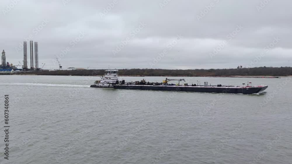 A powerful tug boat diligently guides a fuel barge away from a bustling port in the USA, ensuring the safe and efficient transport of vital energy resources across the waterways. A powerful tug boat diligently guides a fuel barge away from a bustling port in the USA, ensuring the safe and efficient transport of vital energy resources across the waterways.