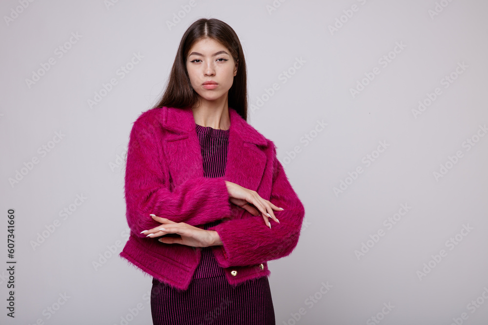 Fashion photo of a beautiful elegant young asian woman in a pretty pink fuchsia dress, jacket posing on white, soft gray background. Studio Shot, portrait. Slim figure. Fashion photo of a beautiful elegant young asian woman in a pretty pink fuchsia dress, jacket posing on white, soft gray background. Studio Shot, portrait. Slim figure.