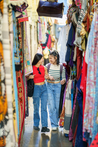 Two Chinese women tourists shopping clothes in street bazaar
