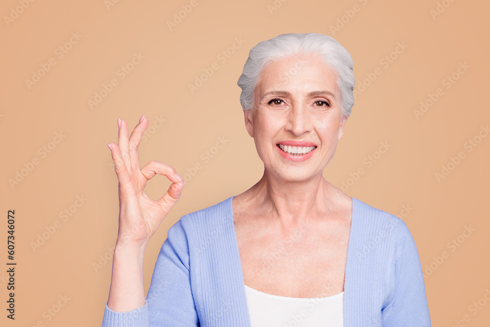Close up portrait of happy elderly woman looking at the camera showing ok sign isolated on bright violet background Close up portrait of happy elderly woman looking at the camera showing ok sign isolated on bright violet background