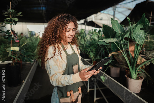 Cool woman working in a greenhouse using a tablet