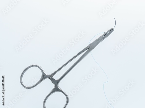 Surgical needle and thread on a suture scissors isolated on a white background