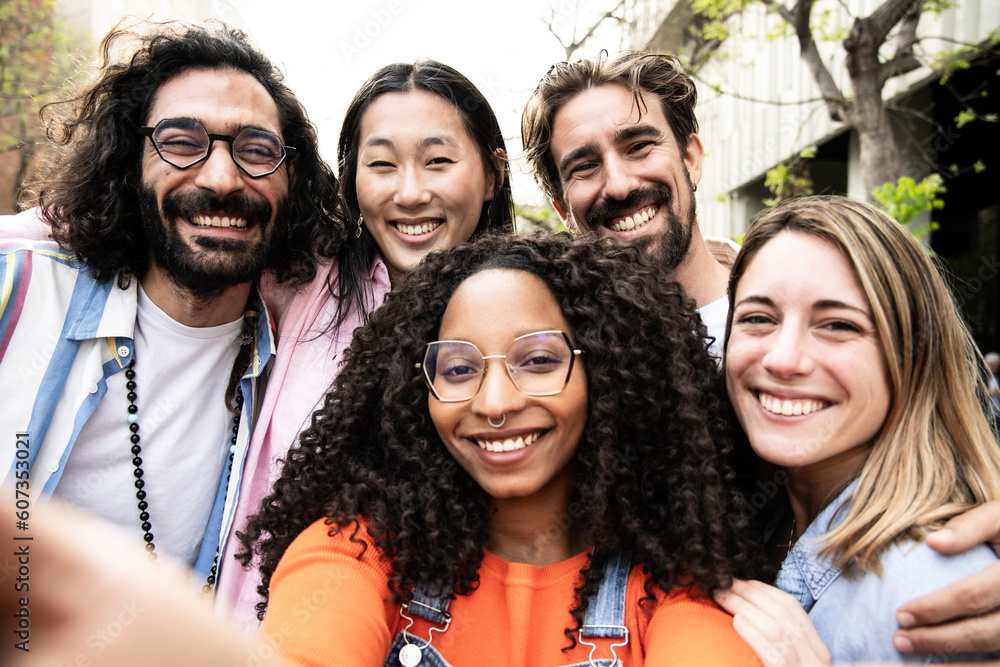 Diverse group of friends taking a selfie in the street.Cheerful multiracial group of young hipsters taking a picture outside and looking at camera.