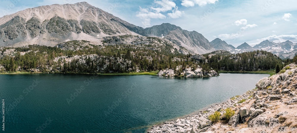 Panoramic shot of a Mammoth mountain lake with snowy trees and mountains in the background