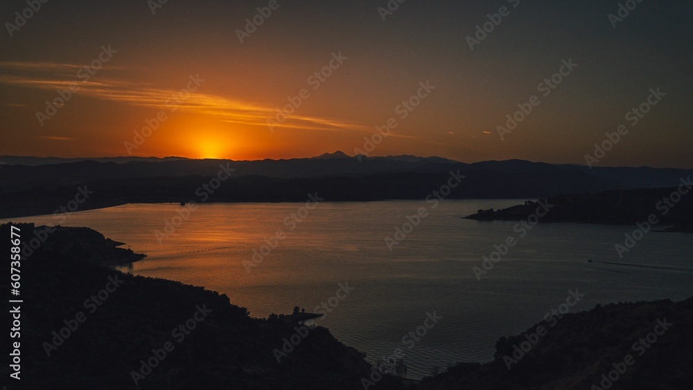 Dramatic scenery of a vibrant sunset in the sky over a lake in the evening in a rural area Dramatic scenery of a vibrant sunset in the sky over a lake in the evening in a rural area