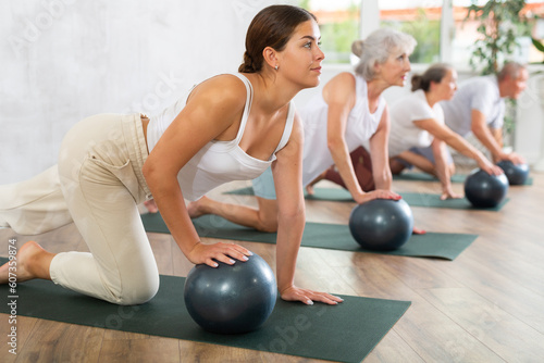 Group of elderly active people doing soft ball exercises during group pilates class in fitness studio