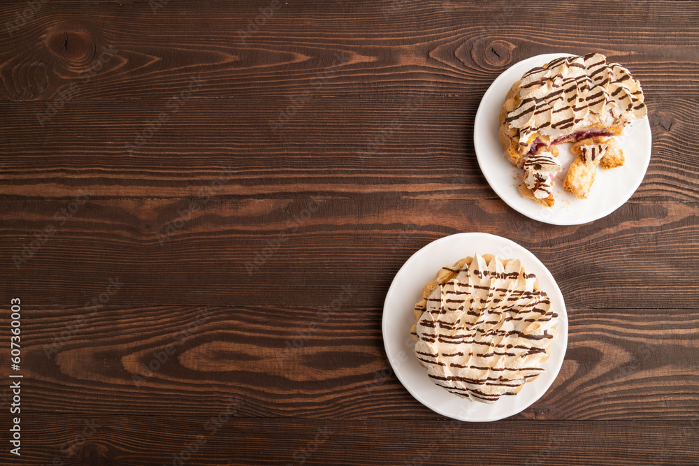 Tartlets with meringue cream and cup of coffee on brown wooden, top view, copy space. Tartlets with meringue cream and cup of coffee on brown wooden, top view, copy space.