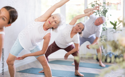 Active elderly women and man practicing various yoga positions during training