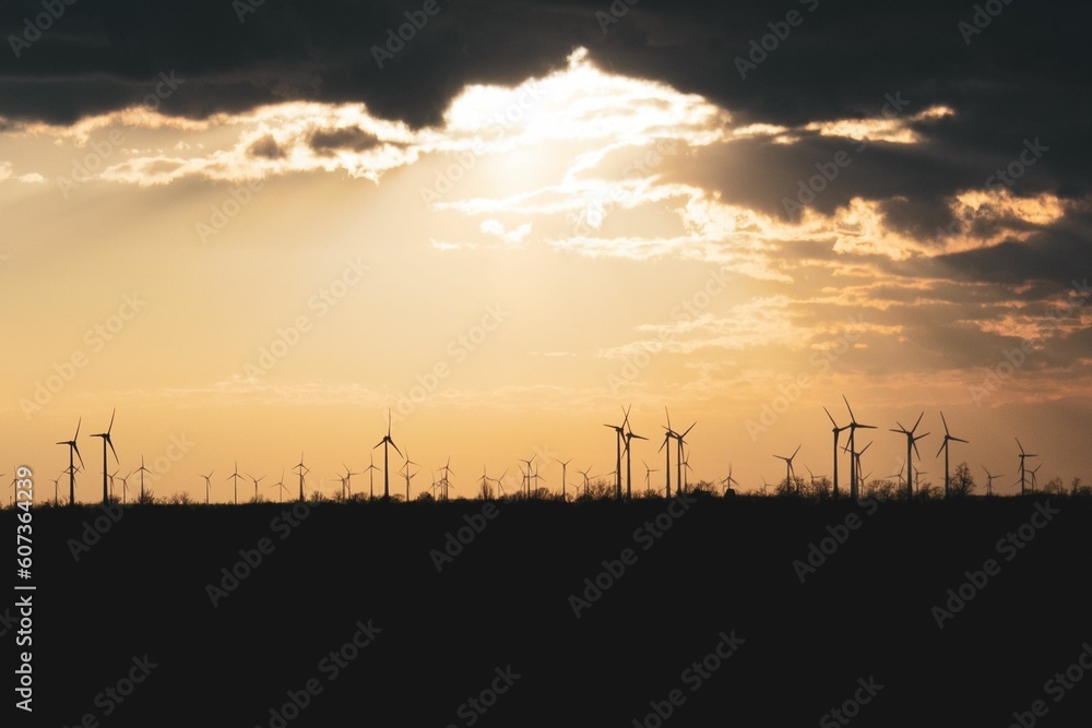 Beautiful view of silhouettes of windmills in the field with mesmerizing sky at sunset
