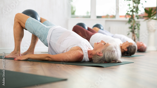 Foto Group of elderly people in sportswear practicing pilates on mat in fitness studi