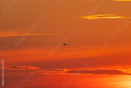 An airplane in the sky after takeoff at sunset.